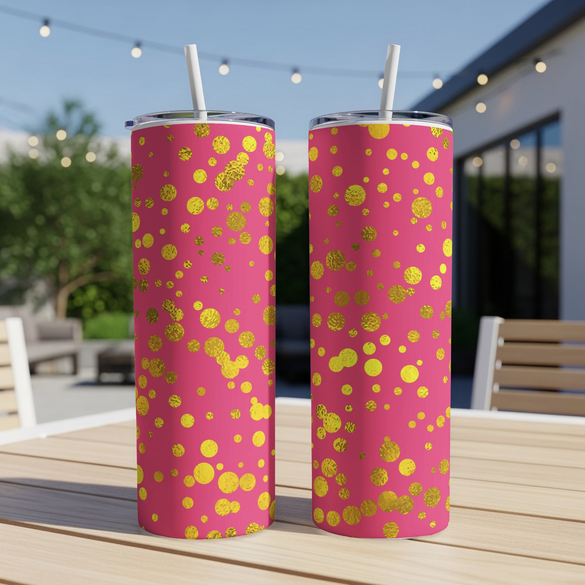 Two pink tumblers with gold polka dots, each with a white lid and straw.