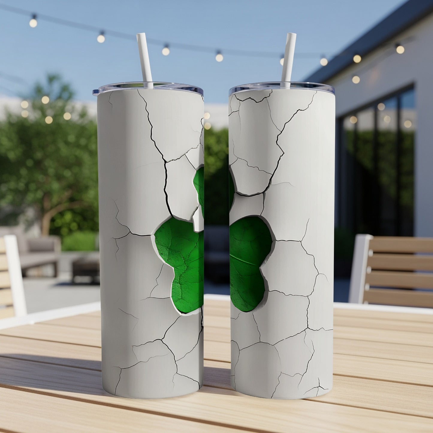 Two white cracked tumblers revealing a green shamrock on outdoor patio table.