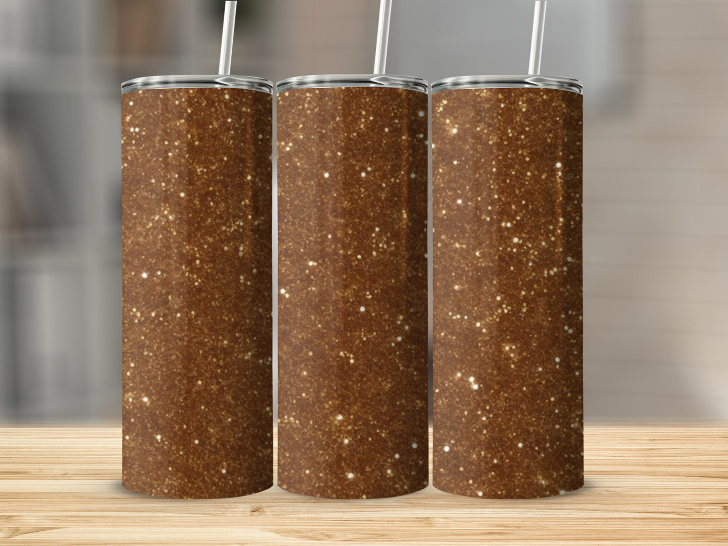 Three brown glitter tumblers with straws stand on a wooden surface.
