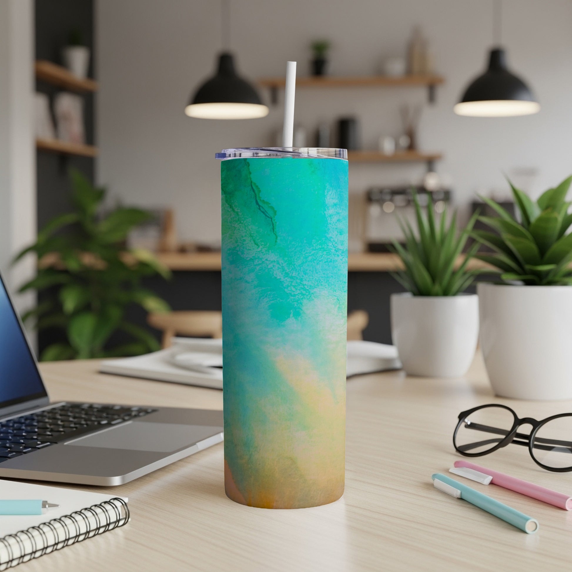 Turquoise and tan marbled tumbler with a white straw on a desk.