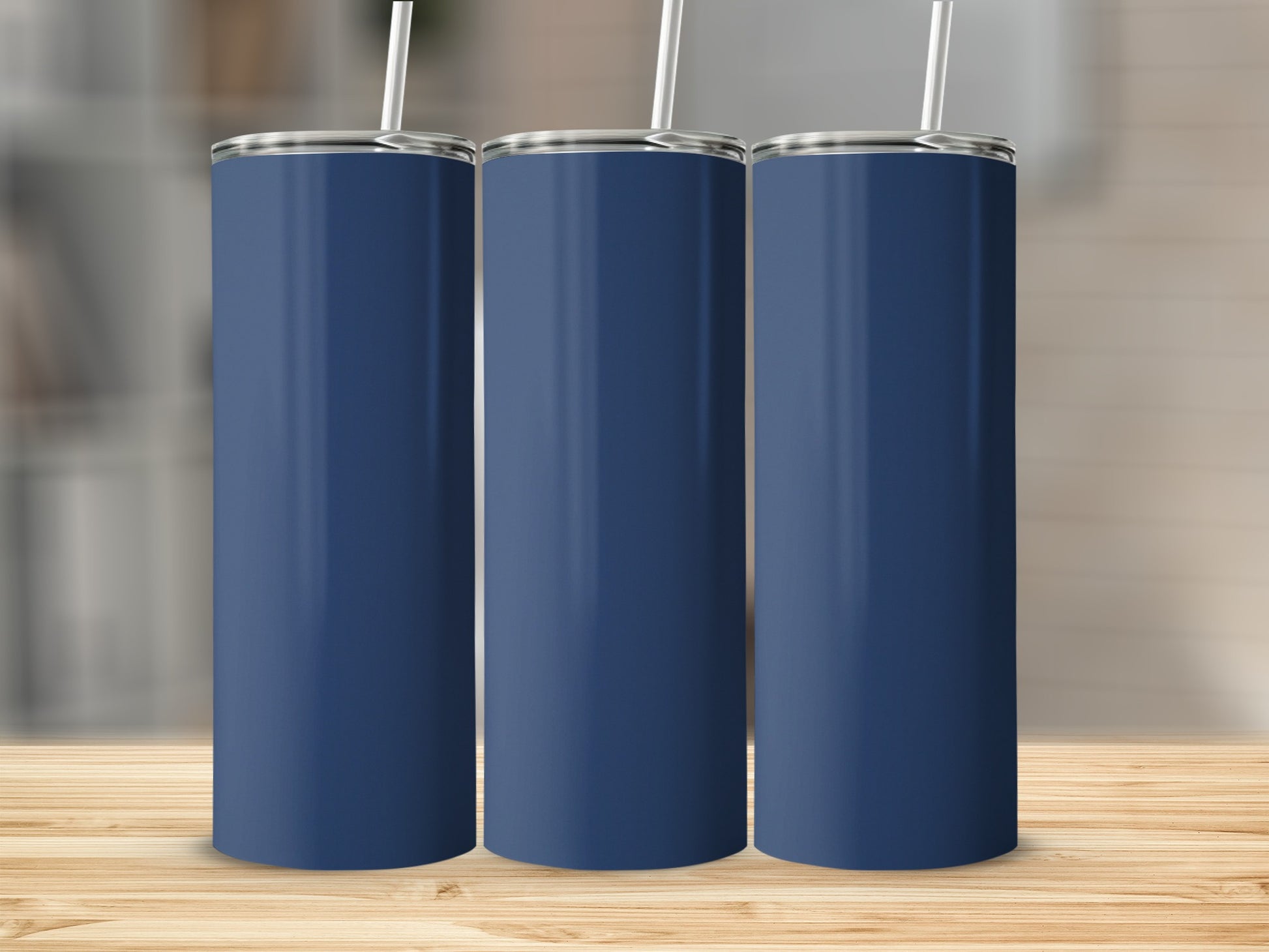 Three navy blue tumblers with white straws stand on a wooden surface.
