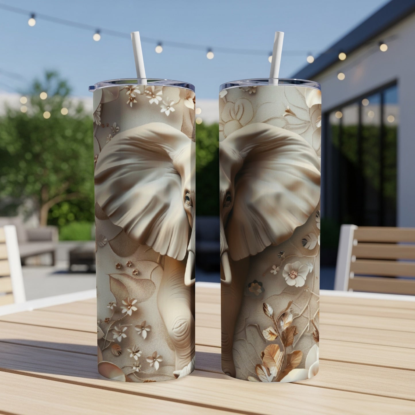 Two tumblers with embossed elephant and floral designs on a table.