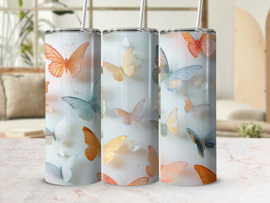 Three tumblers with colorful butterfly designs and straws.
