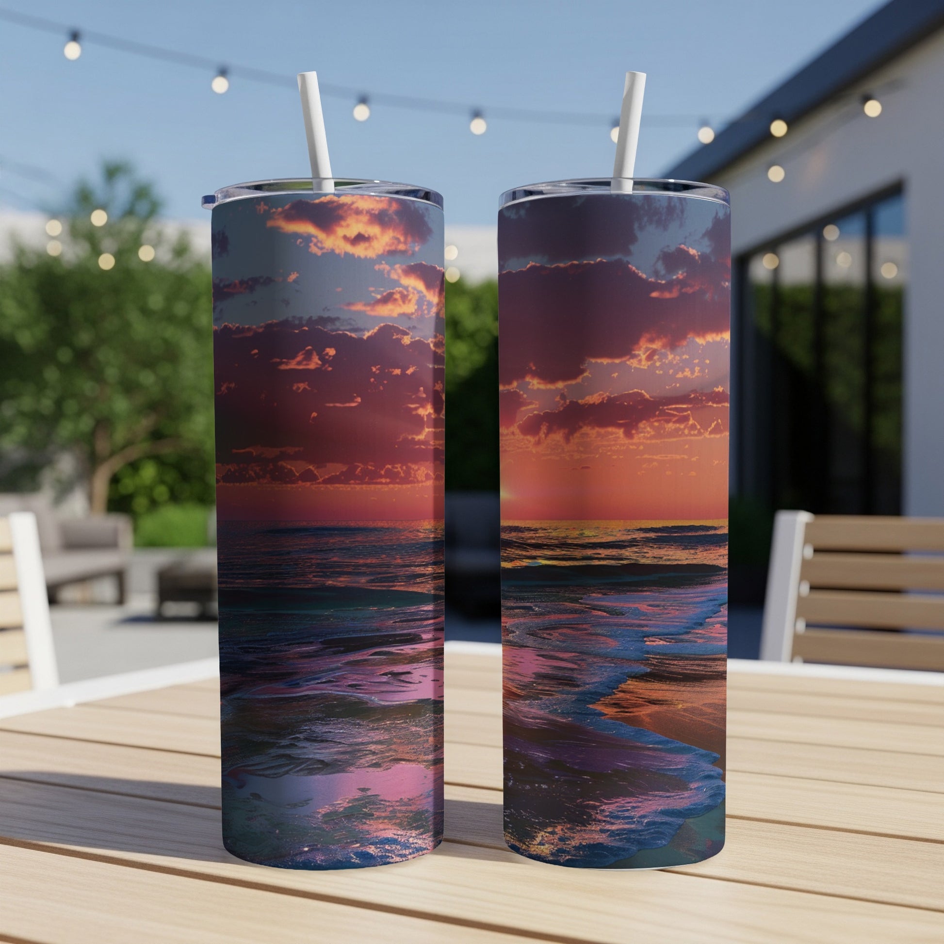 Two tumblers with ocean sunset design on wooden table outdoors.