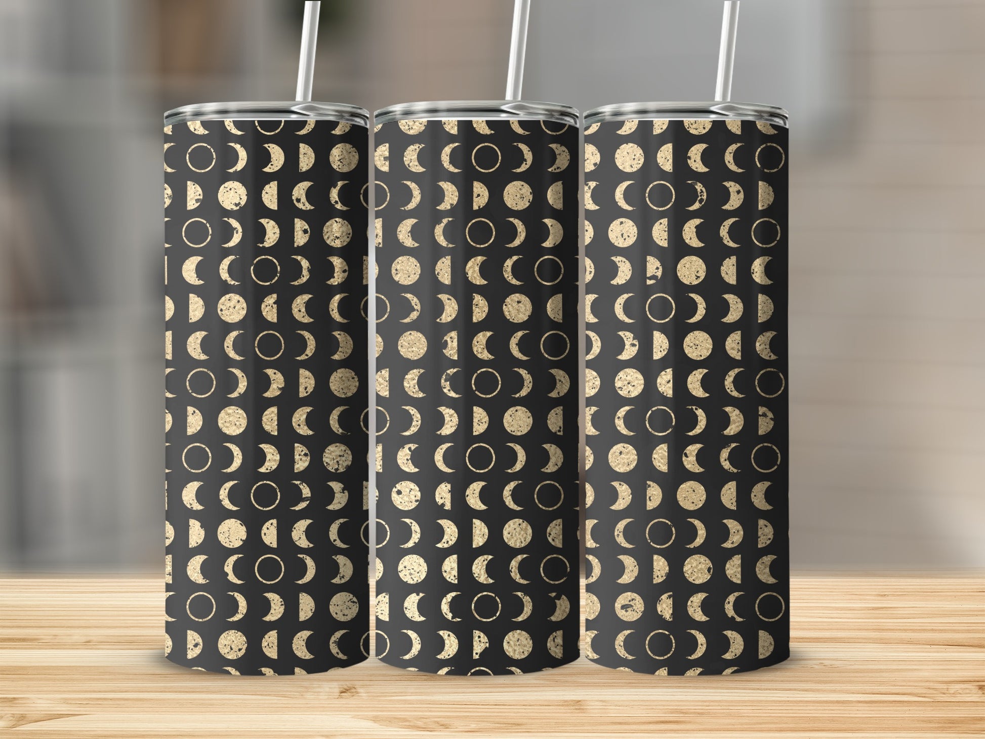 Three tumblers with a black background and gold moon phase pattern, each with a straw.