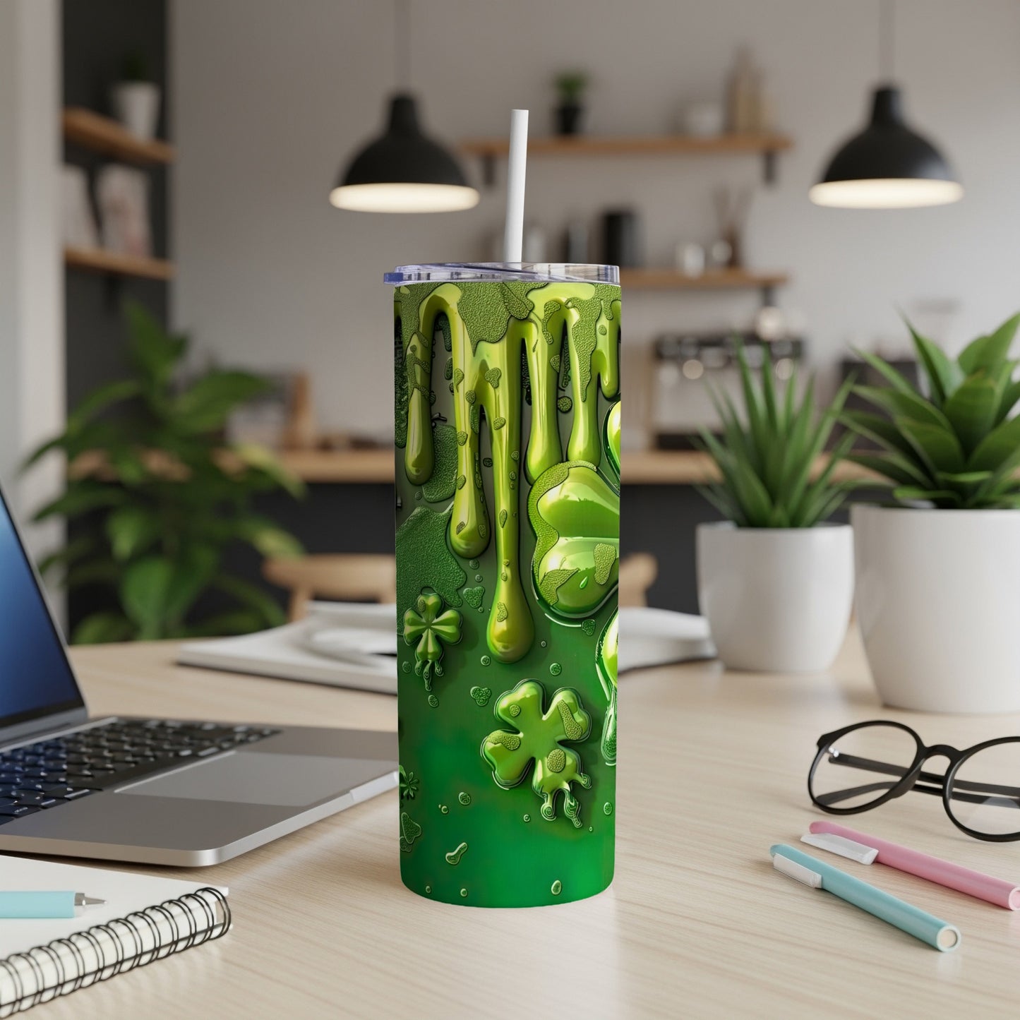 Green tumbler with dripping slime and shamrock pattern on a desk.
