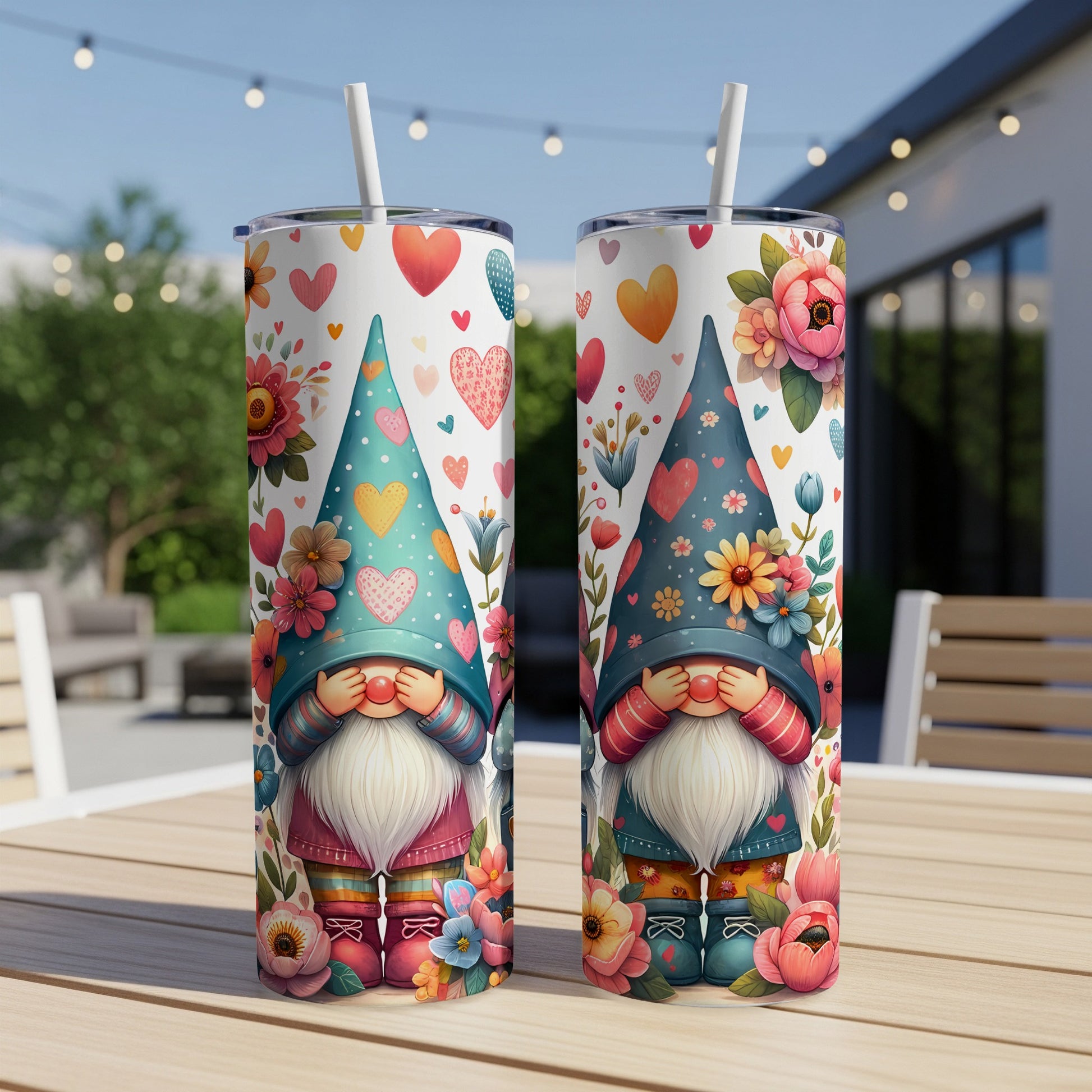 Two decorative tumblers with gnome and floral designs on a table.