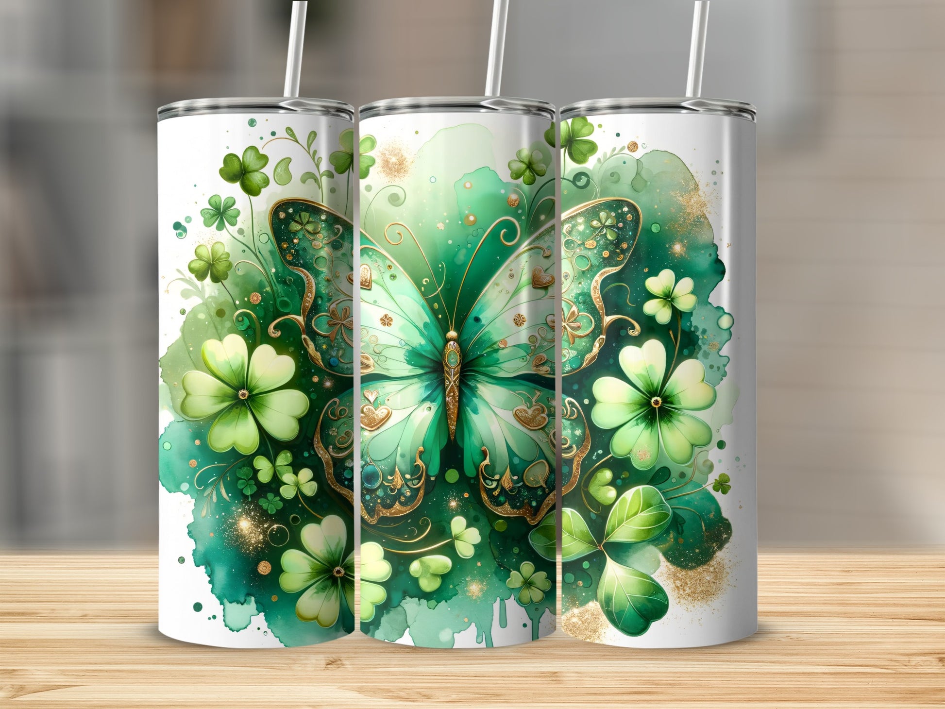 Green butterfly and shamrocks adorn three tumblers on a wooden surface.
