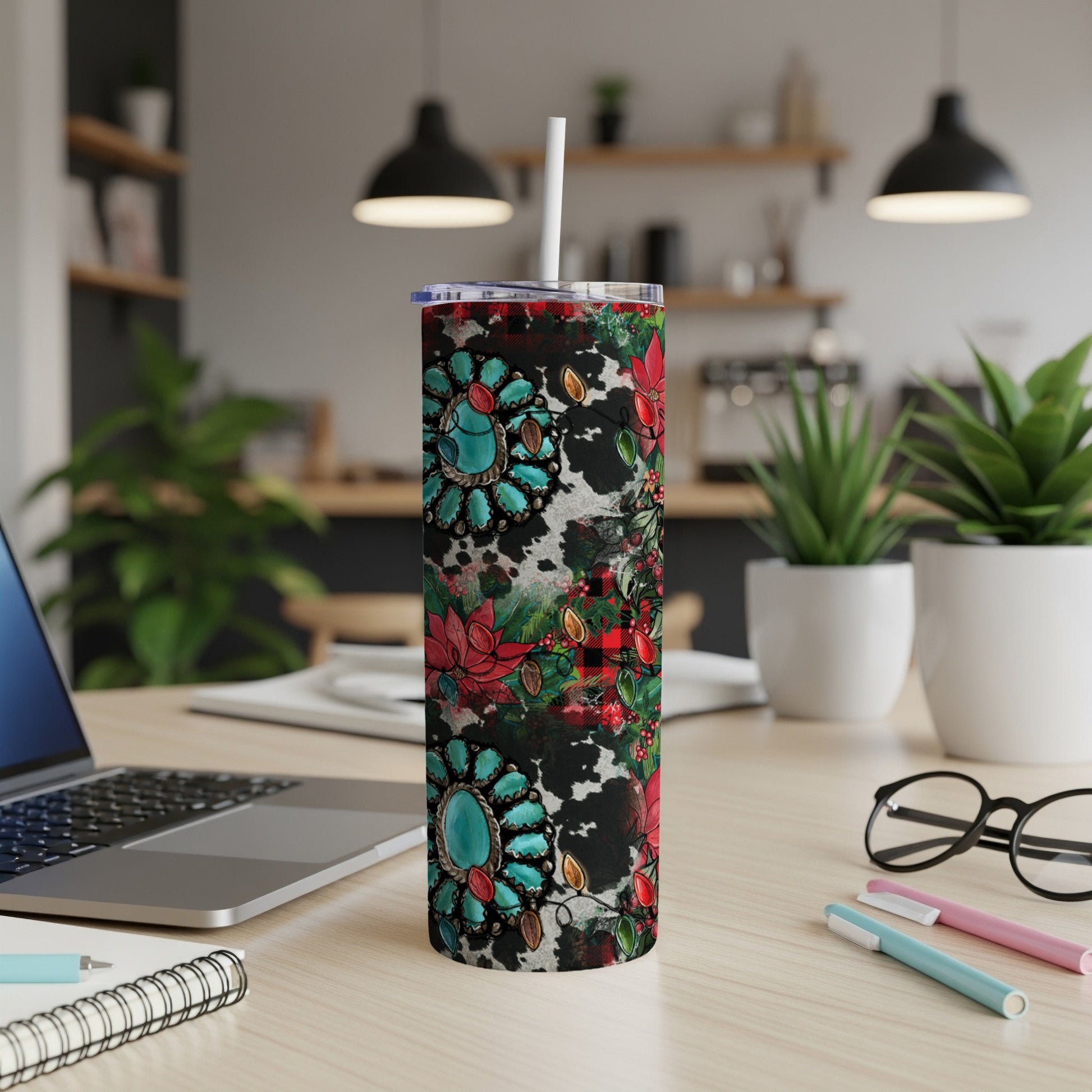 Turquoise, red, and black patterned tumbler with straw on a desk.