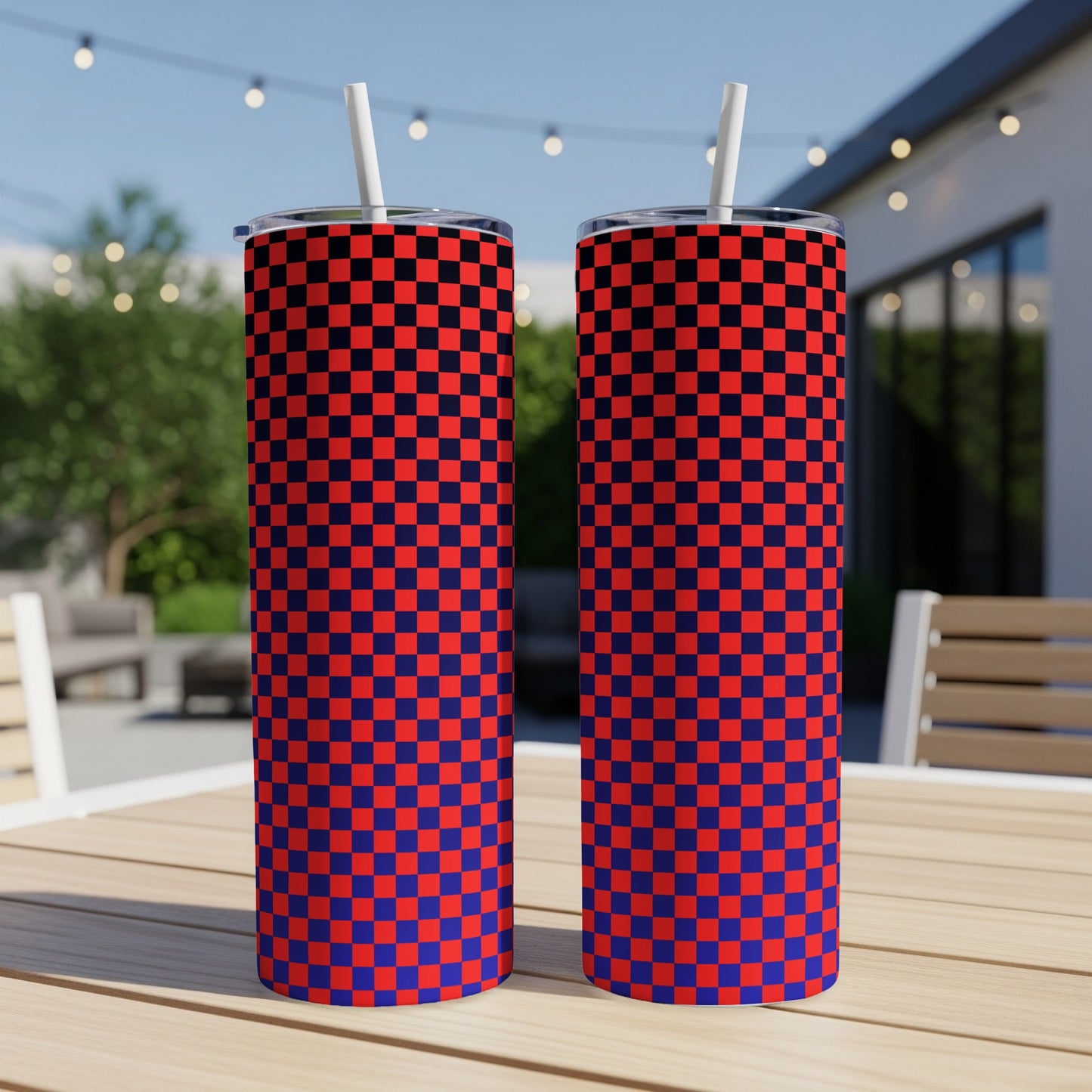Two red and blue checkered tumblers with straws on a wooden table.