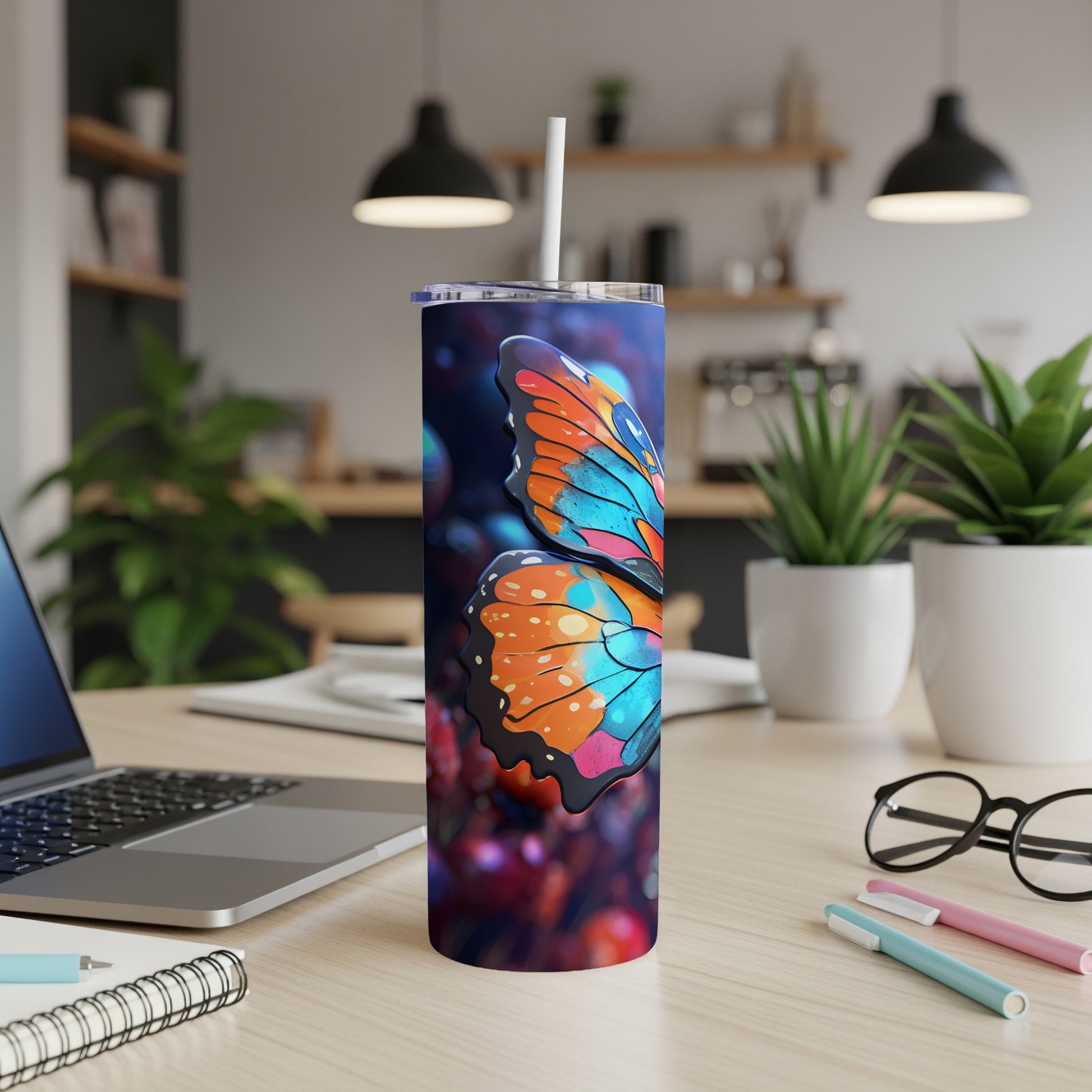 Tall tumbler with a colorful butterfly design and straw on a desk.