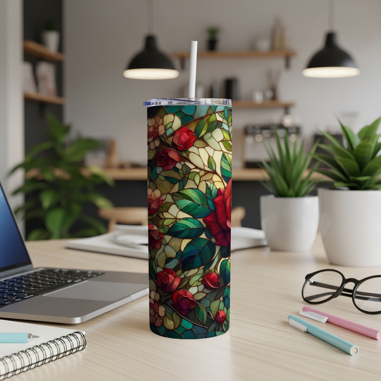 Floral stained glass tumbler with lid and straw on a desk.