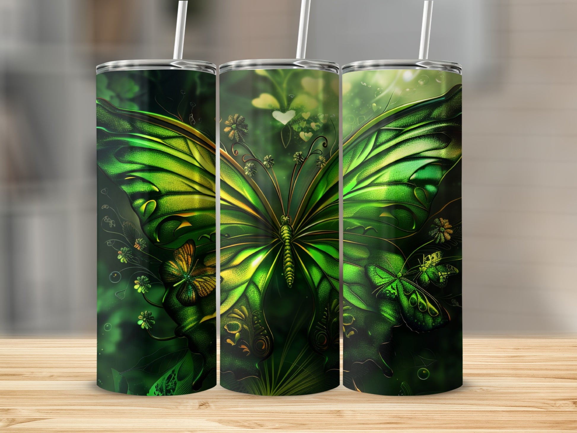 Green butterfly design on three tumblers against a blurred green background.