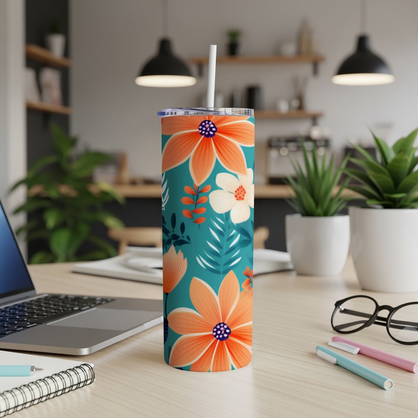 Teal tumbler with orange and white floral pattern and straw.