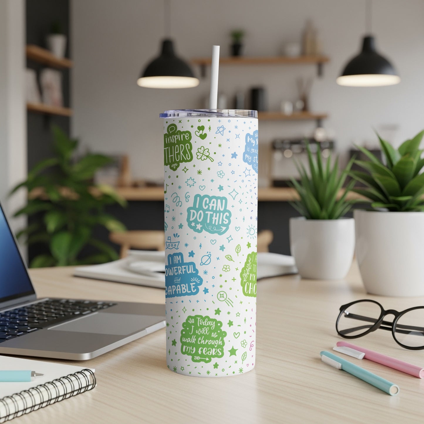 White tumbler with green and blue positive affirmations and floral doodles.