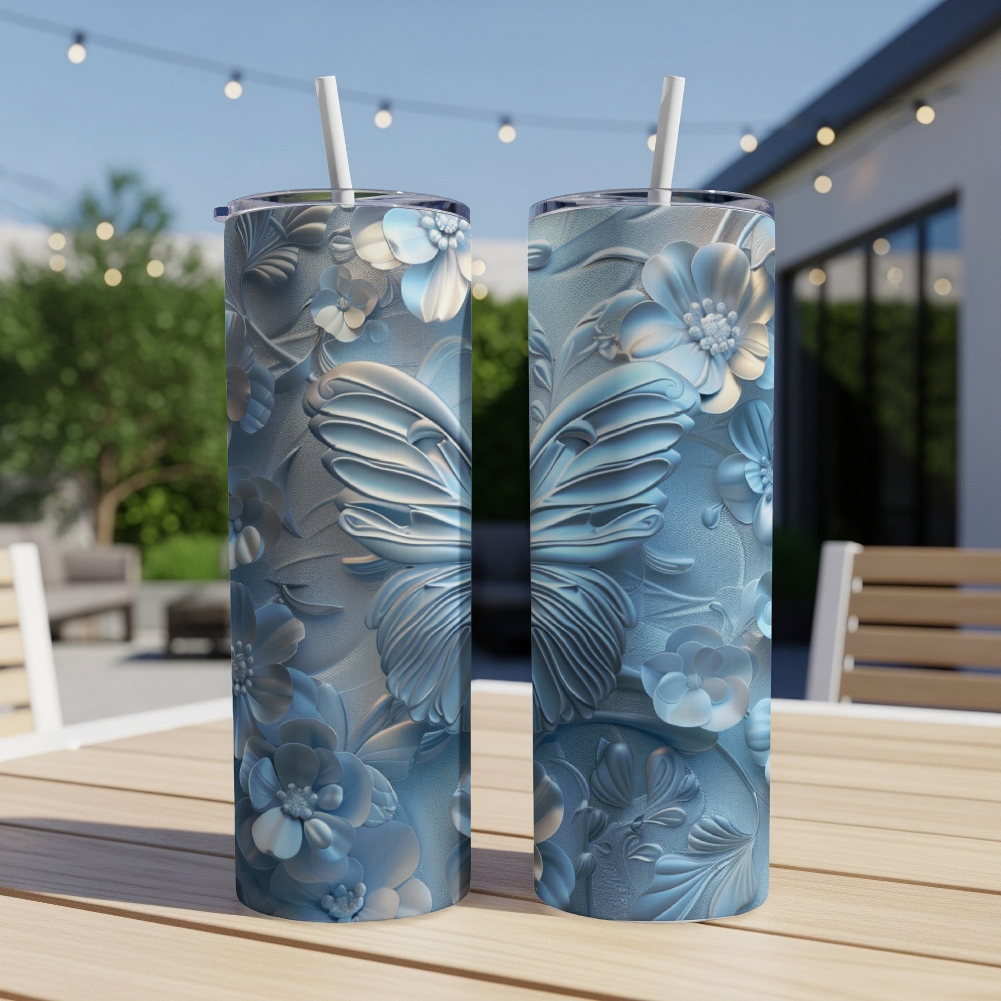 Two blue tumblers with embossed floral and butterfly designs on a wooden table.