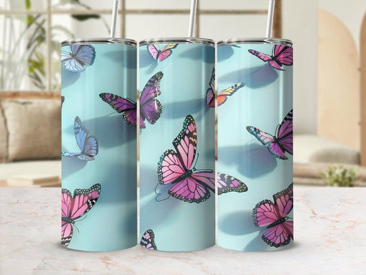 Three tumblers decorated with pink and purple butterflies on a light blue background.
