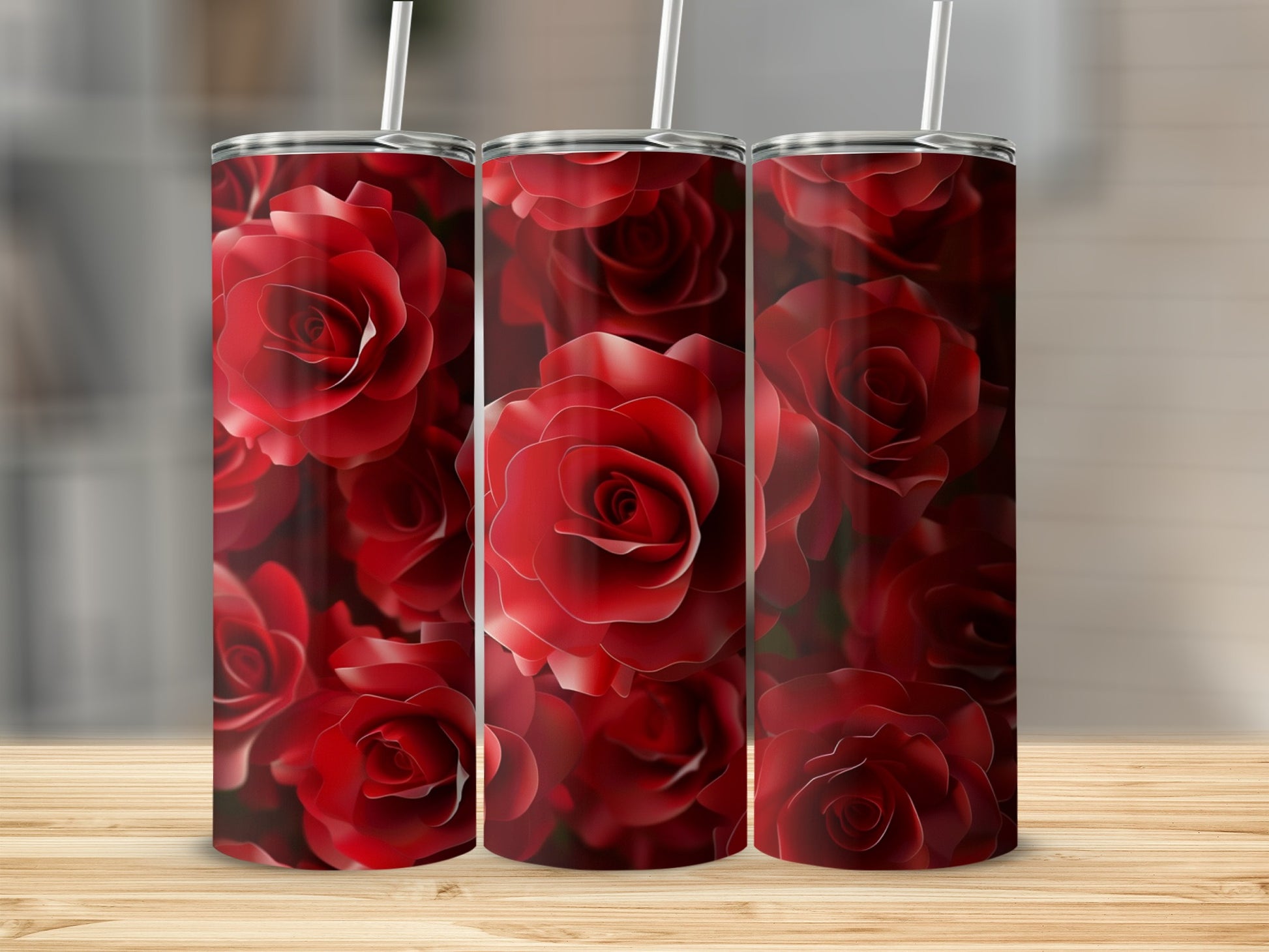 Three tumblers with a repeating pattern of deep red roses on a wooden surface.
