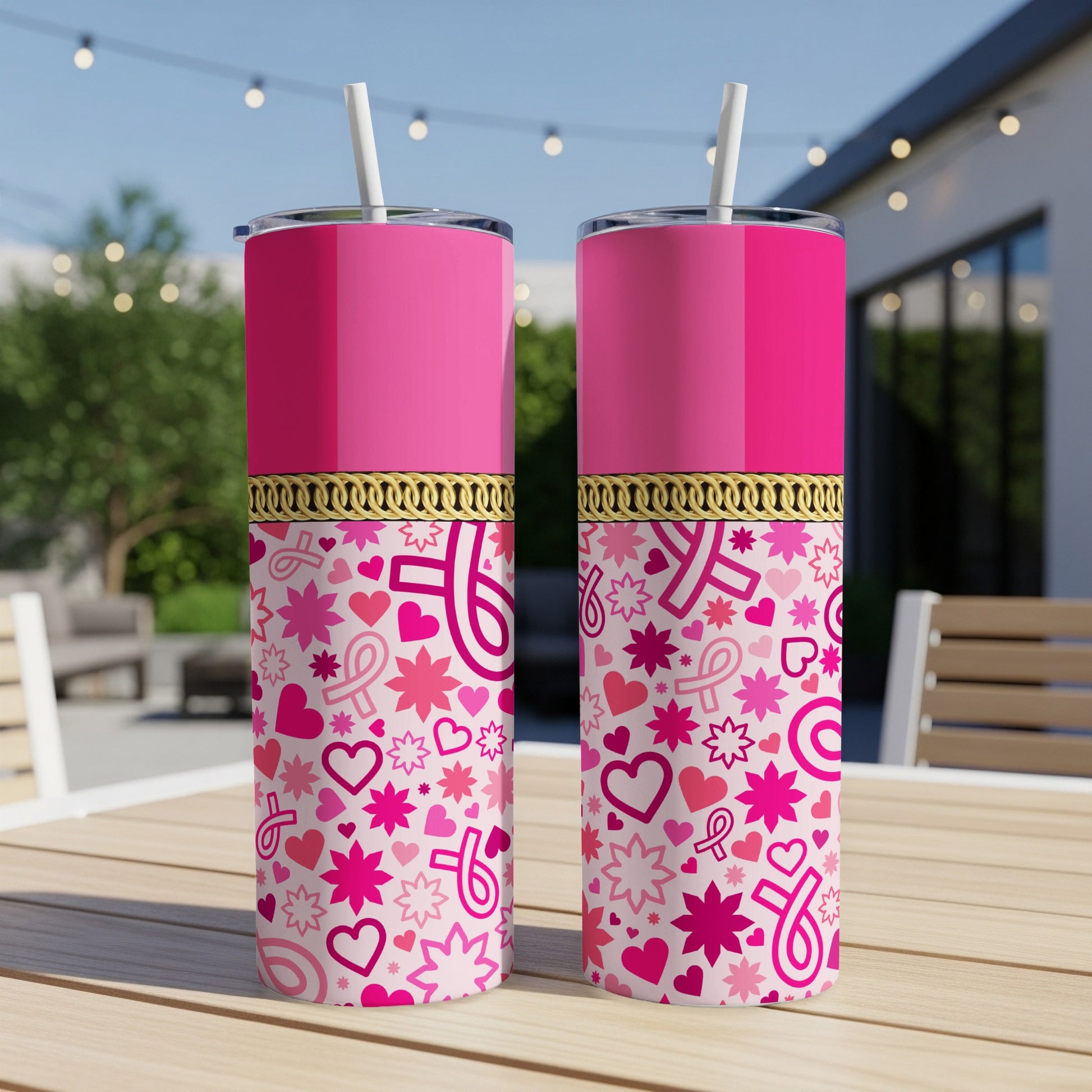 Two pink tumblers with breast cancer ribbon and heart pattern, on a wooden table.