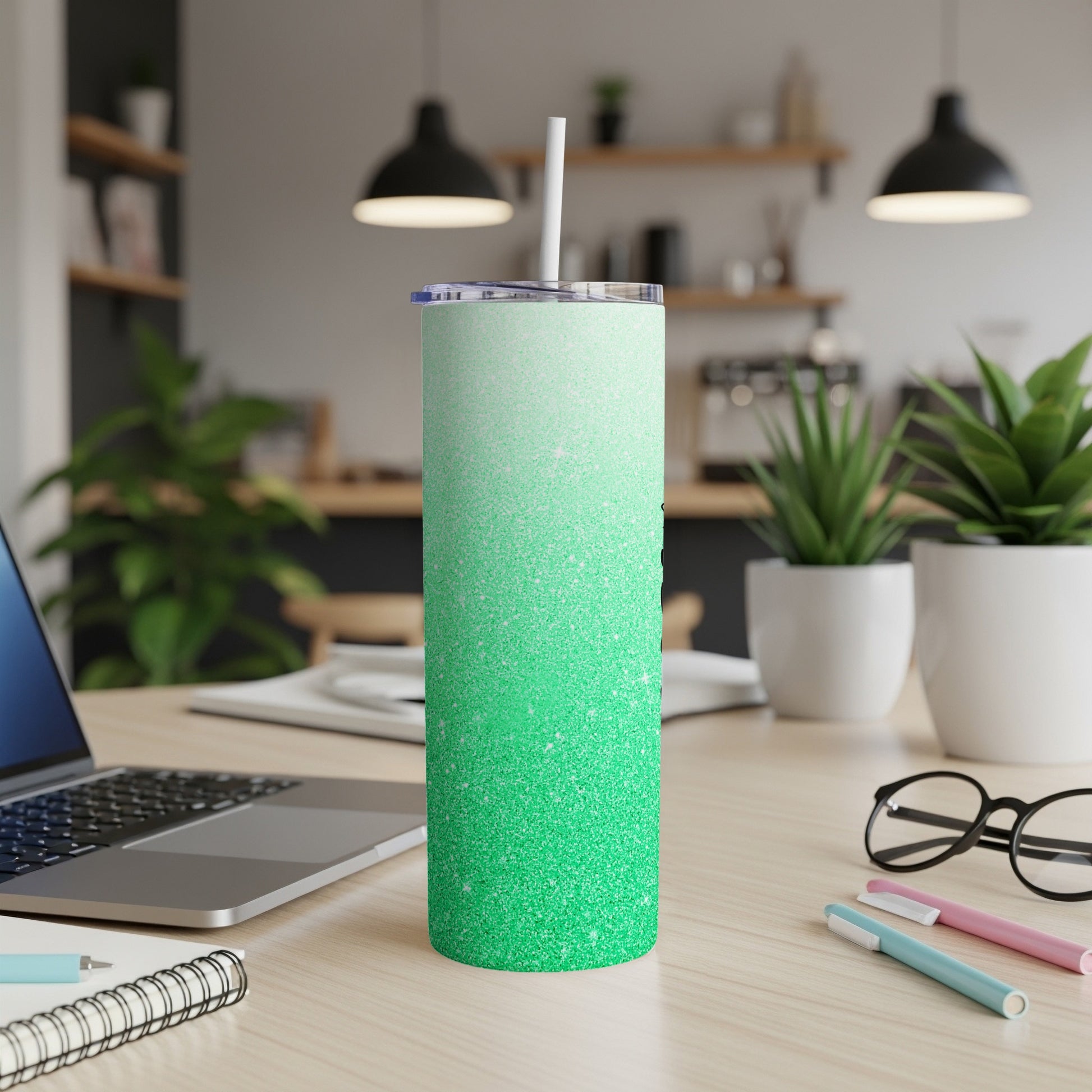 Glitter gradient green tumbler with white straw on a desk.