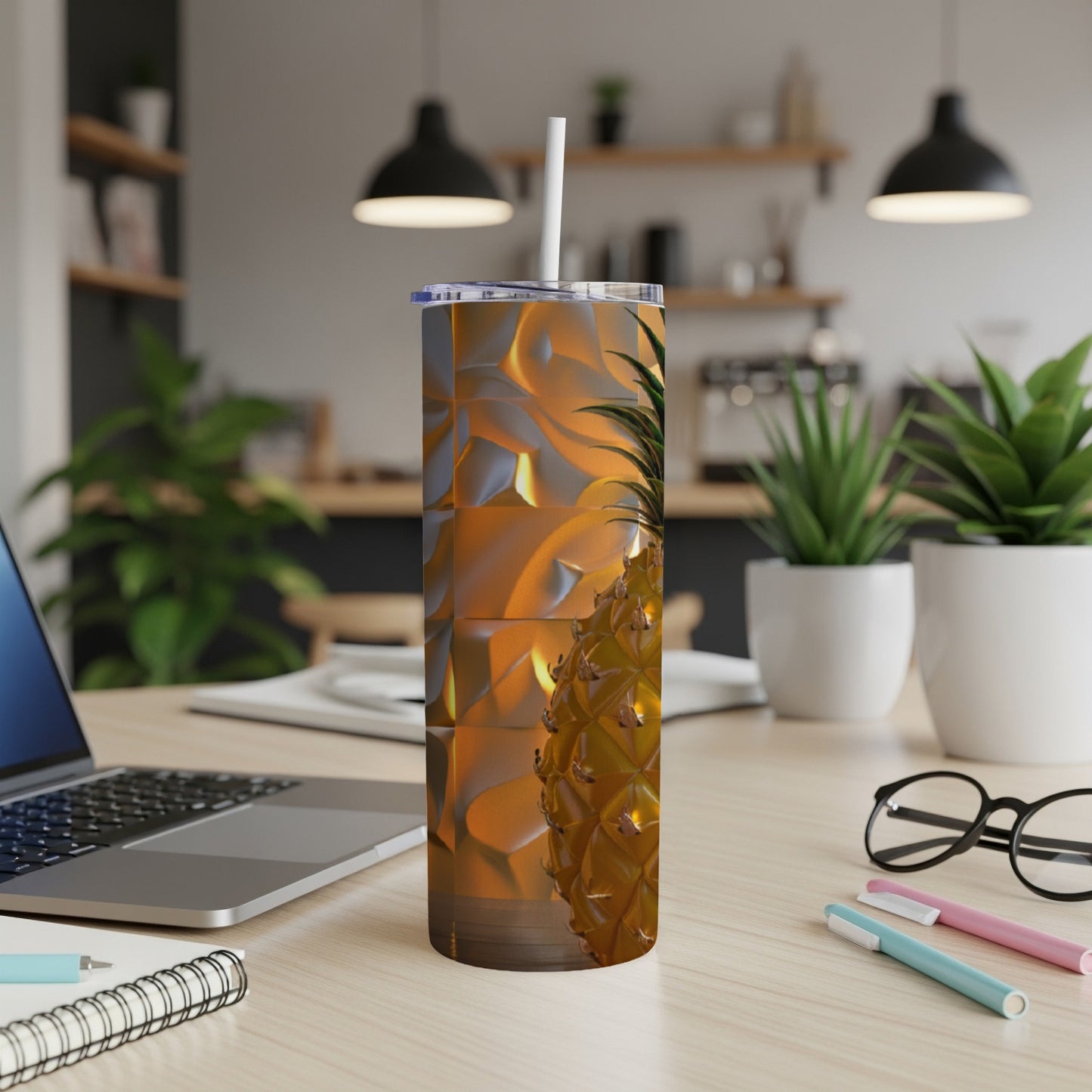 Tumbler with pineapple pattern on a desk next to a laptop.