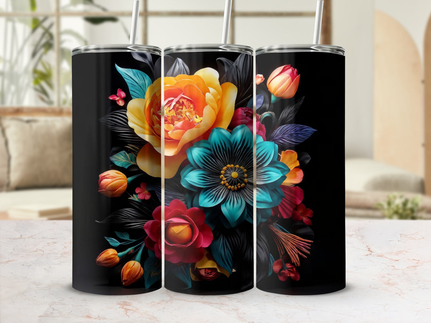 Three tumblers with vibrant floral designs on a marble countertop.