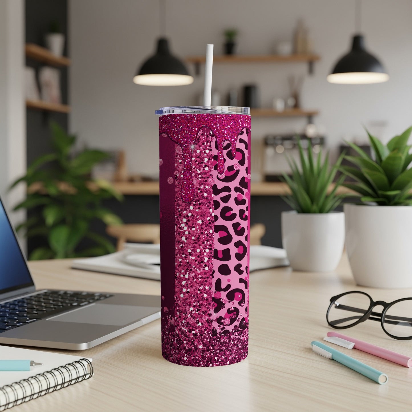 Pink glitter and leopard print tumbler with straw on a desk.
