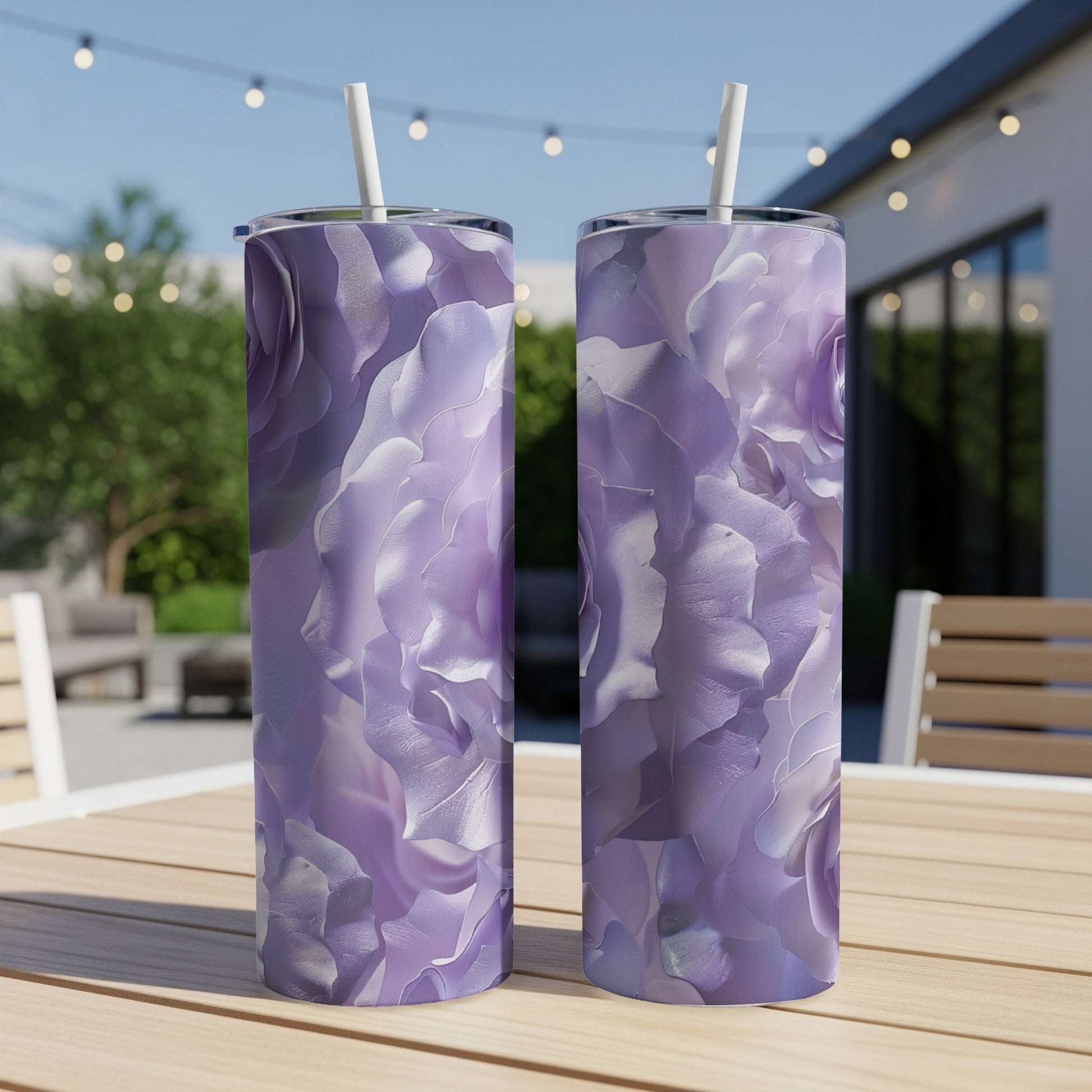 Two purple floral patterned tumblers with straws on a wooden table.