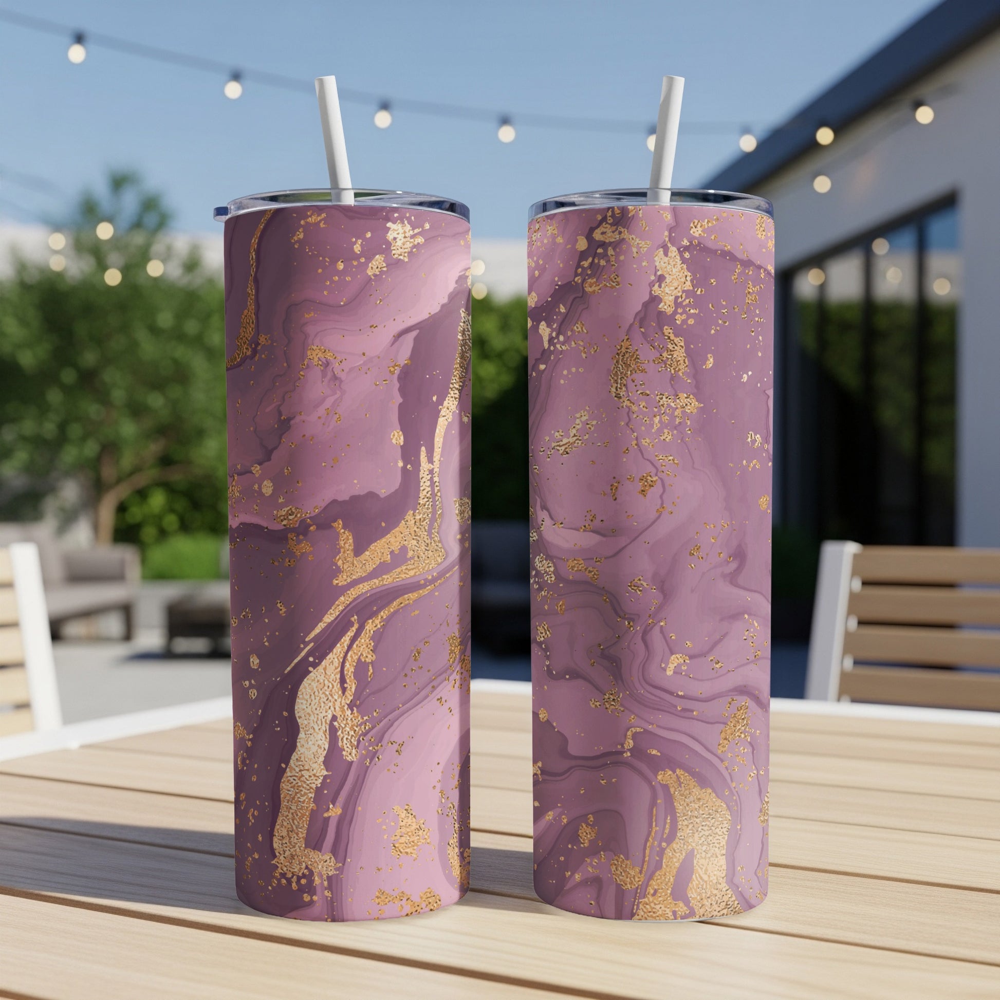 Two purple and gold marble pattern tumblers with straws on a table.