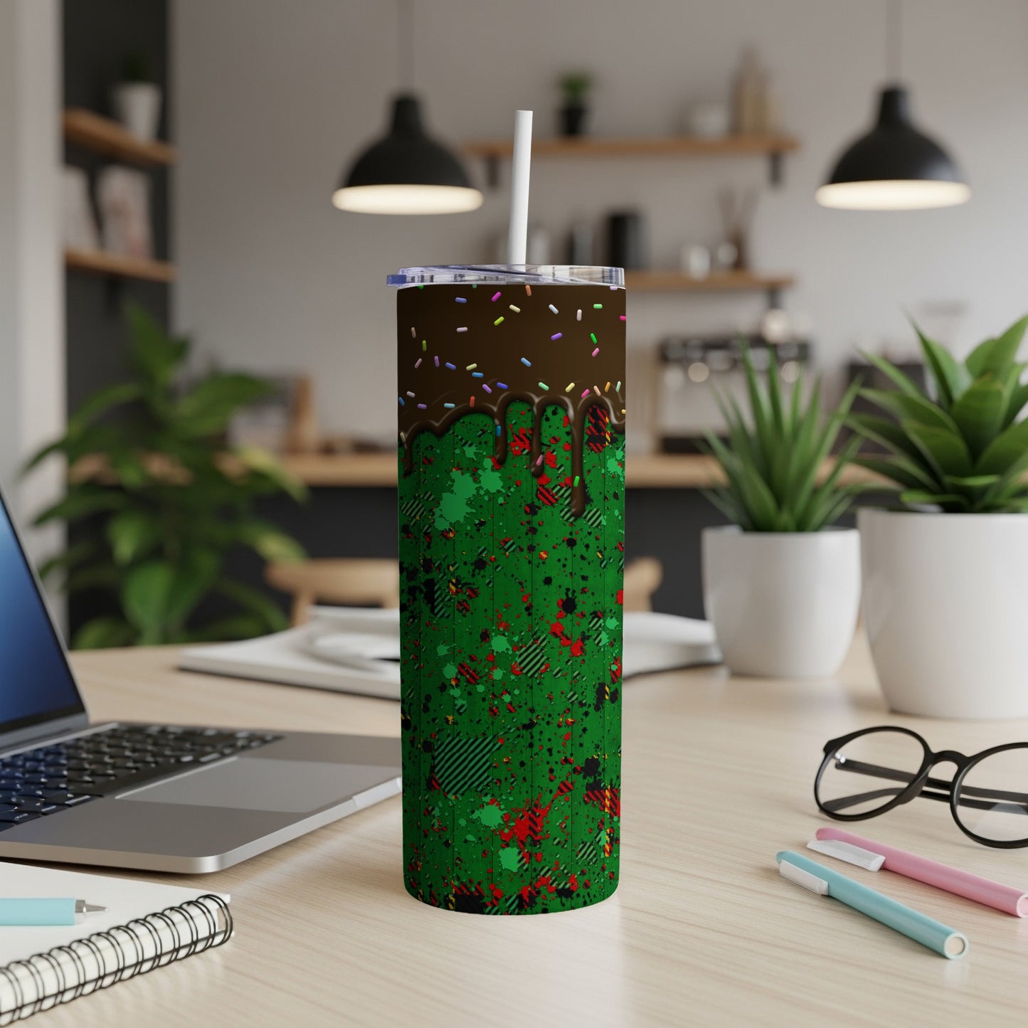 Green tumbler with chocolate drip and sprinkles on desk.