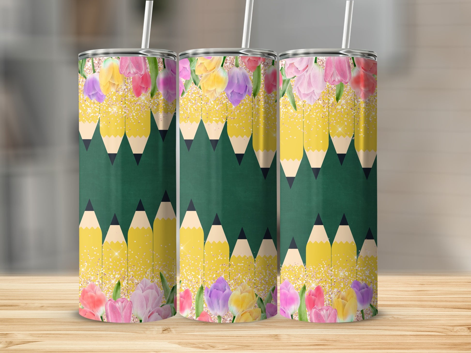Three tumblers with a pencil and floral design on a wooden surface.