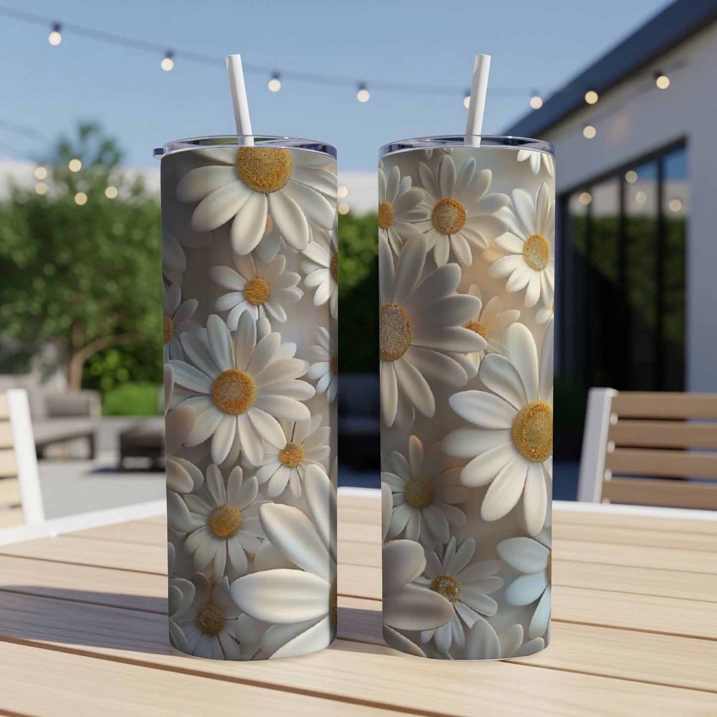 Two white daisy-patterned tumblers with straws stand on a wooden table.