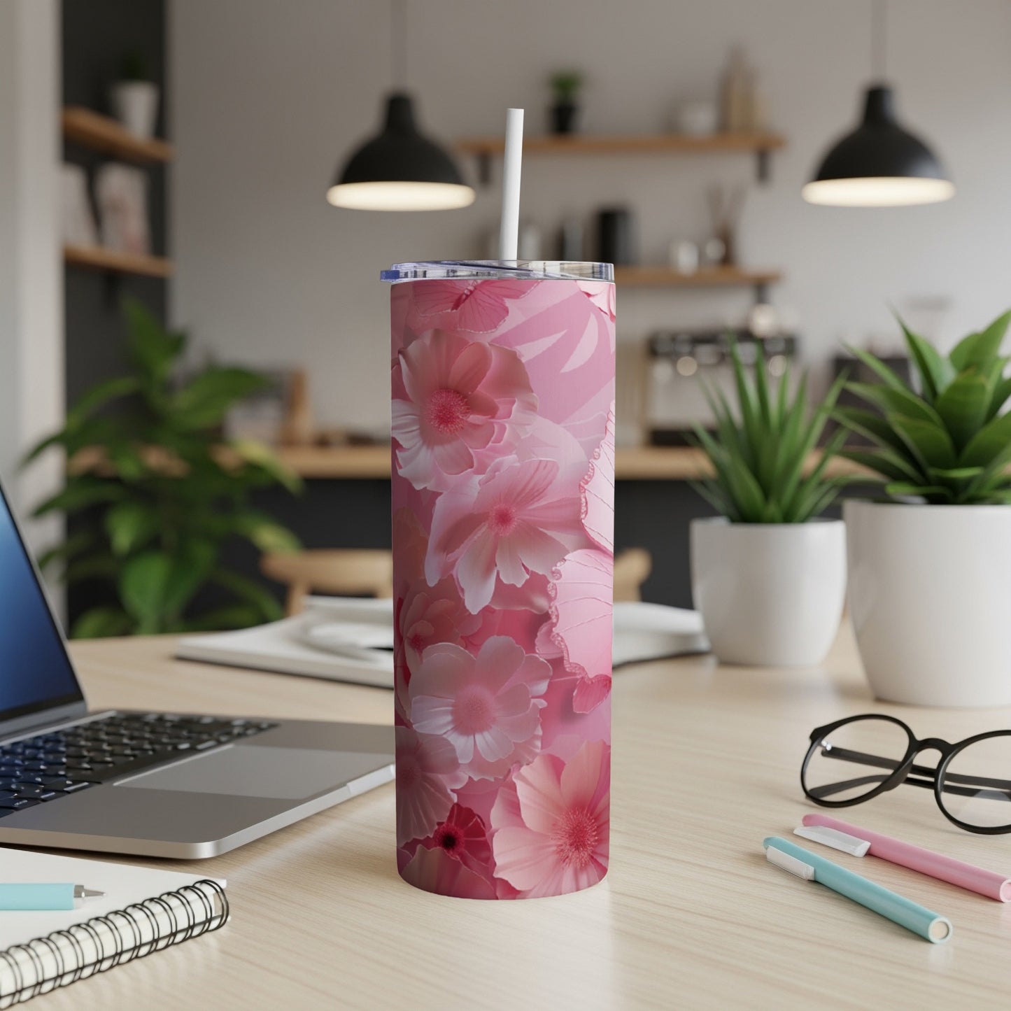 Pink floral patterned tumbler with straw on a desk.