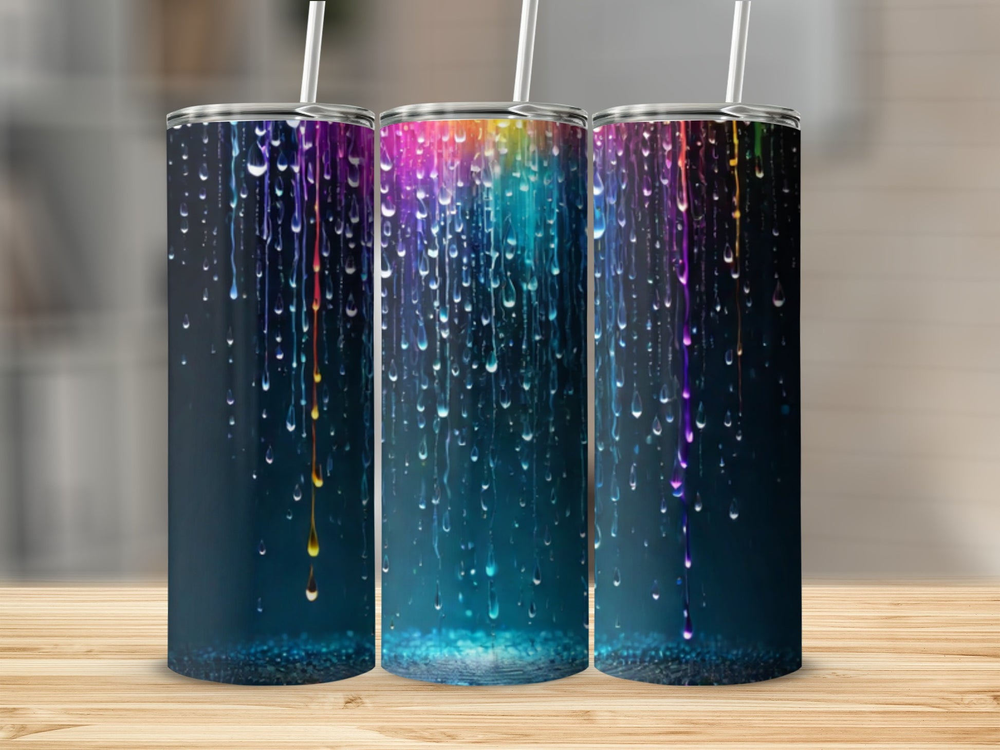 Three tumblers with colorful dripping paint design on a wooden surface.