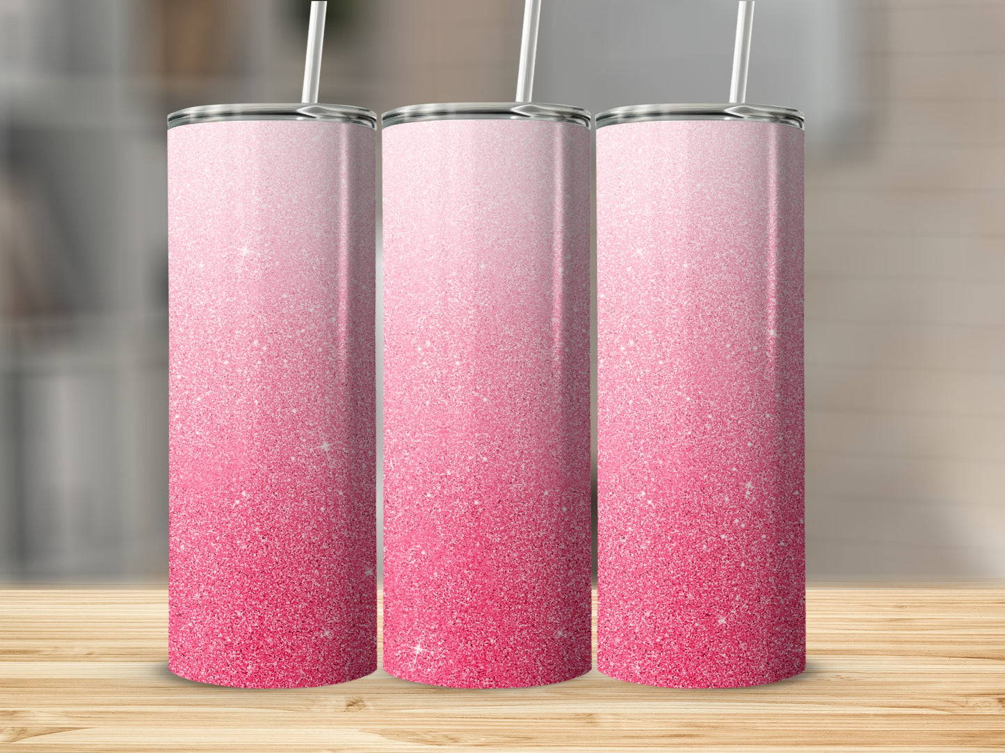 Three tall pink glitter tumblers with straws on a wooden surface.