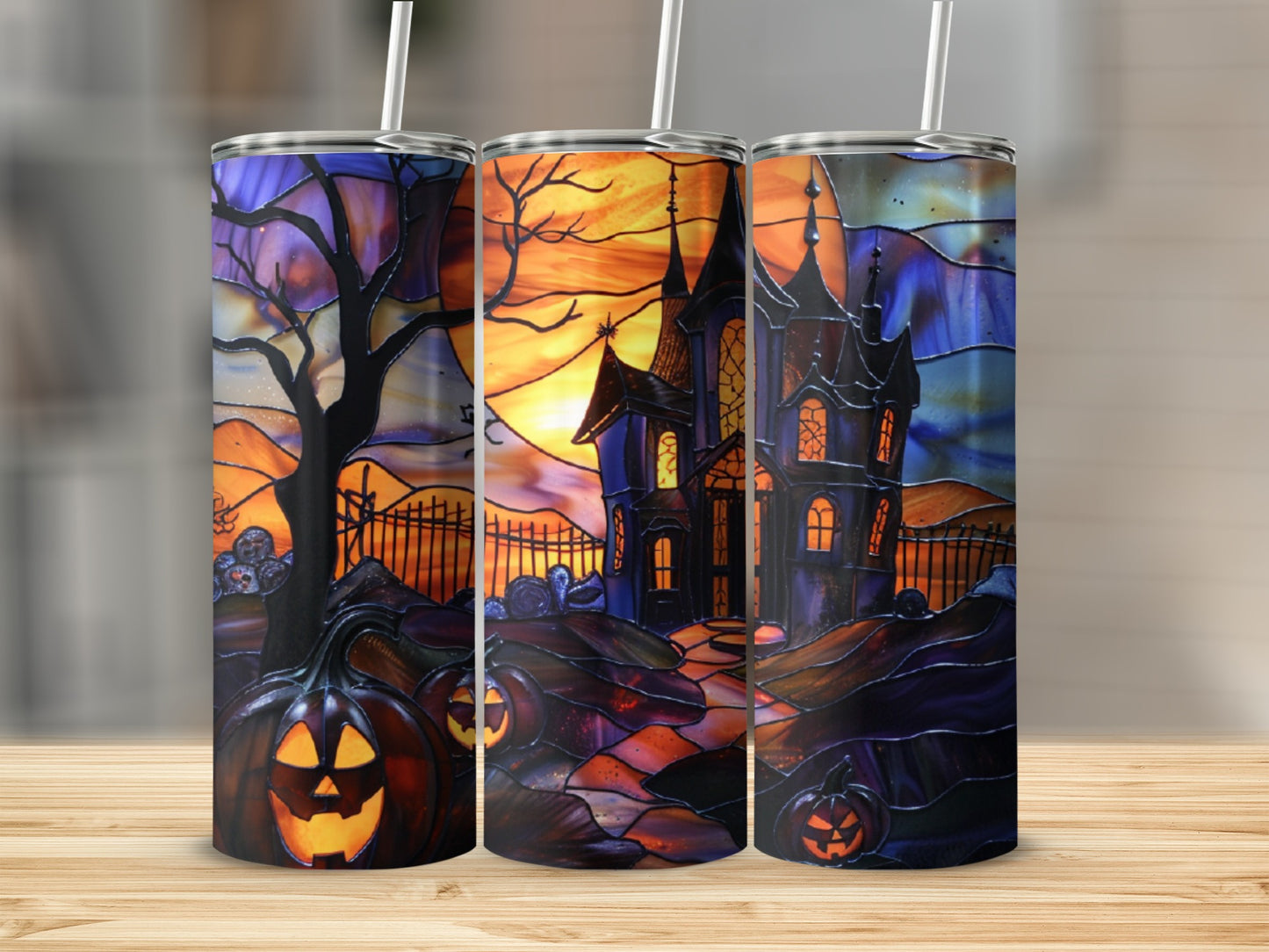 Three Halloween-themed tumblers with stained glass designs of haunted houses and pumpkins.