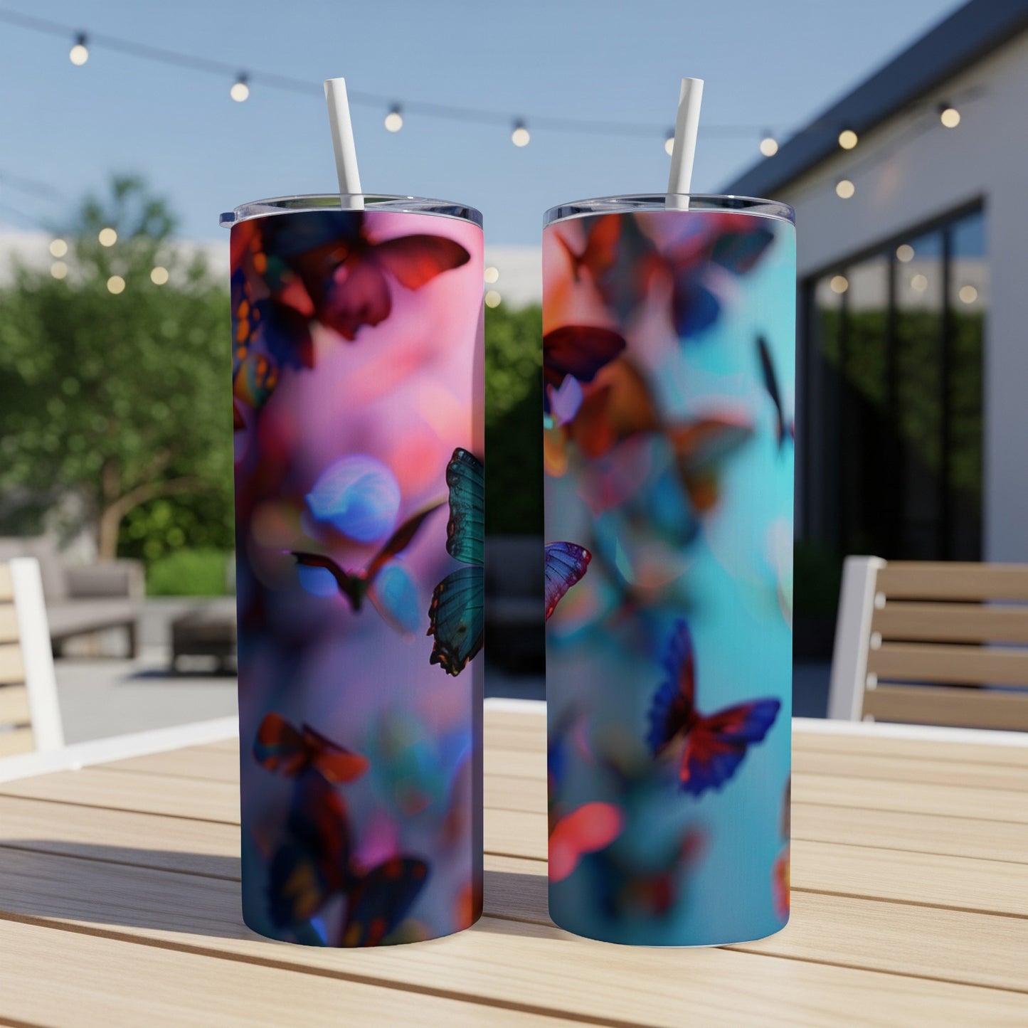 Two tumblers with vibrant butterfly patterns sit on a wooden table outdoors.
