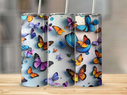 Three tumblers with colorful butterfly designs on a wooden surface.