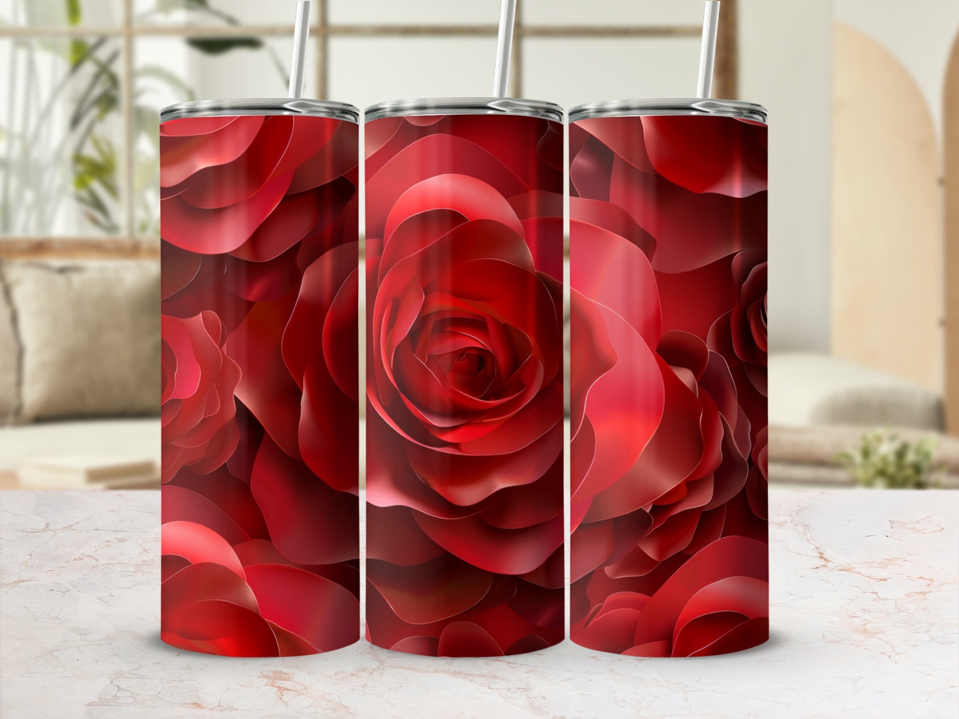 Three red rose patterned tumblers with straws on a marble surface.