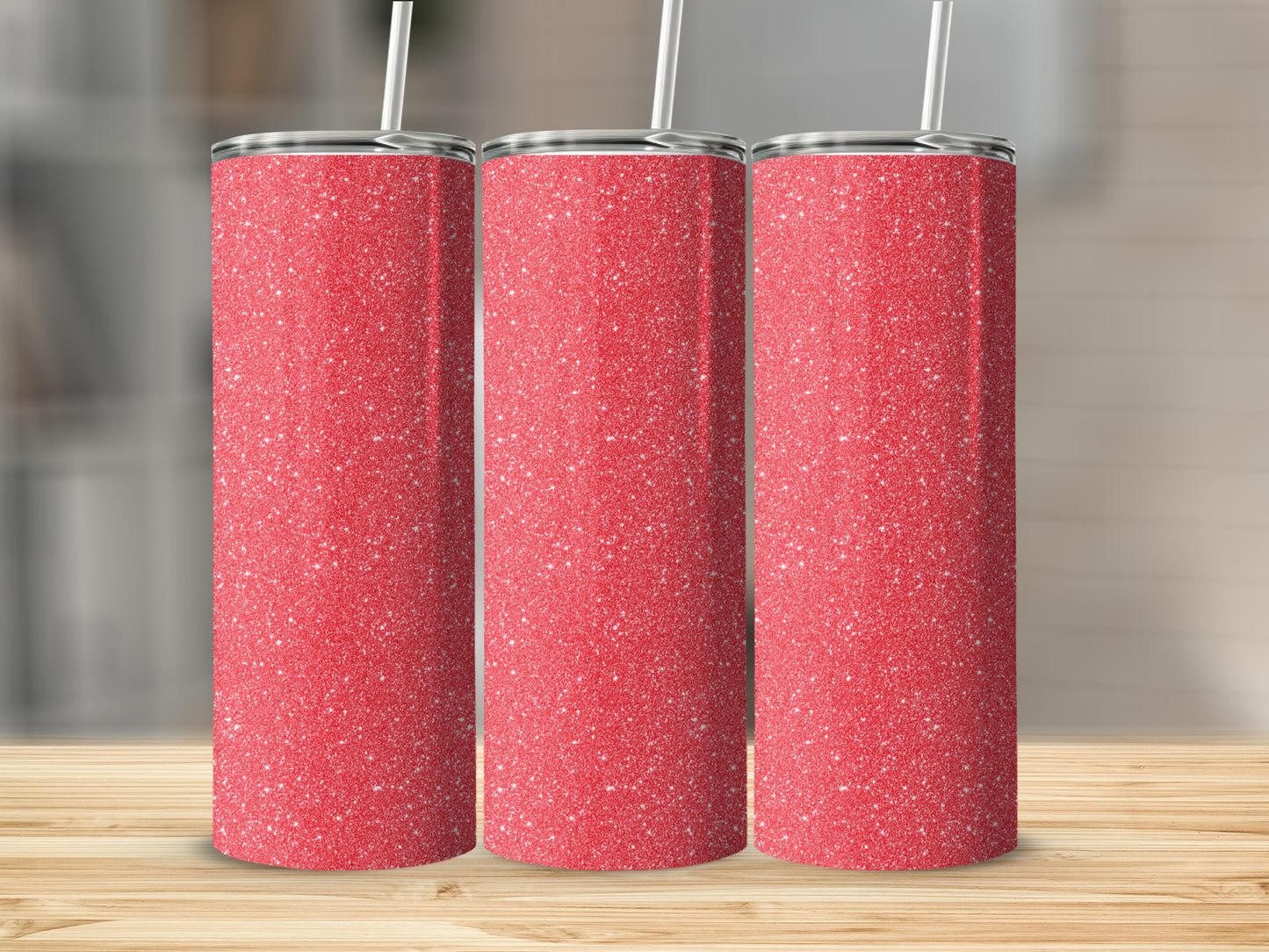 Three red glitter tumblers with white straws stand on a wooden table.