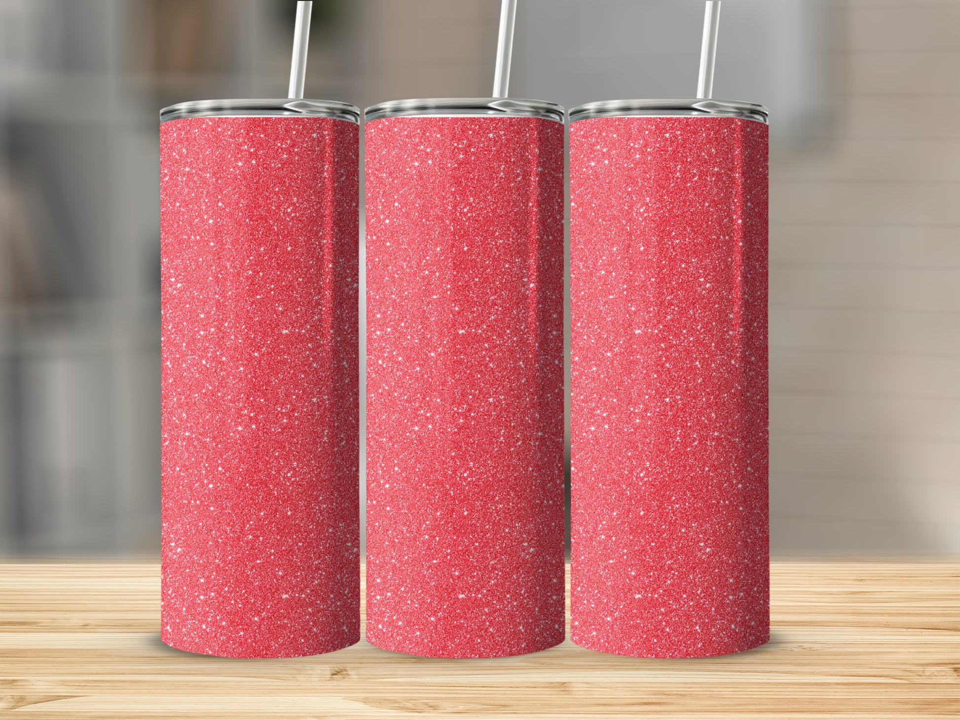 Three red glitter tumblers with white straws stand on a wooden table.
