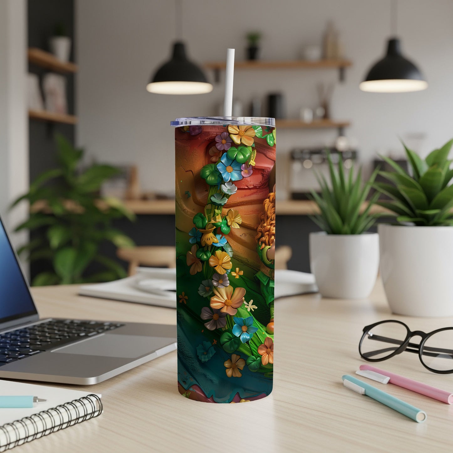 Tumbler with colorful floral design and straw on a desk.