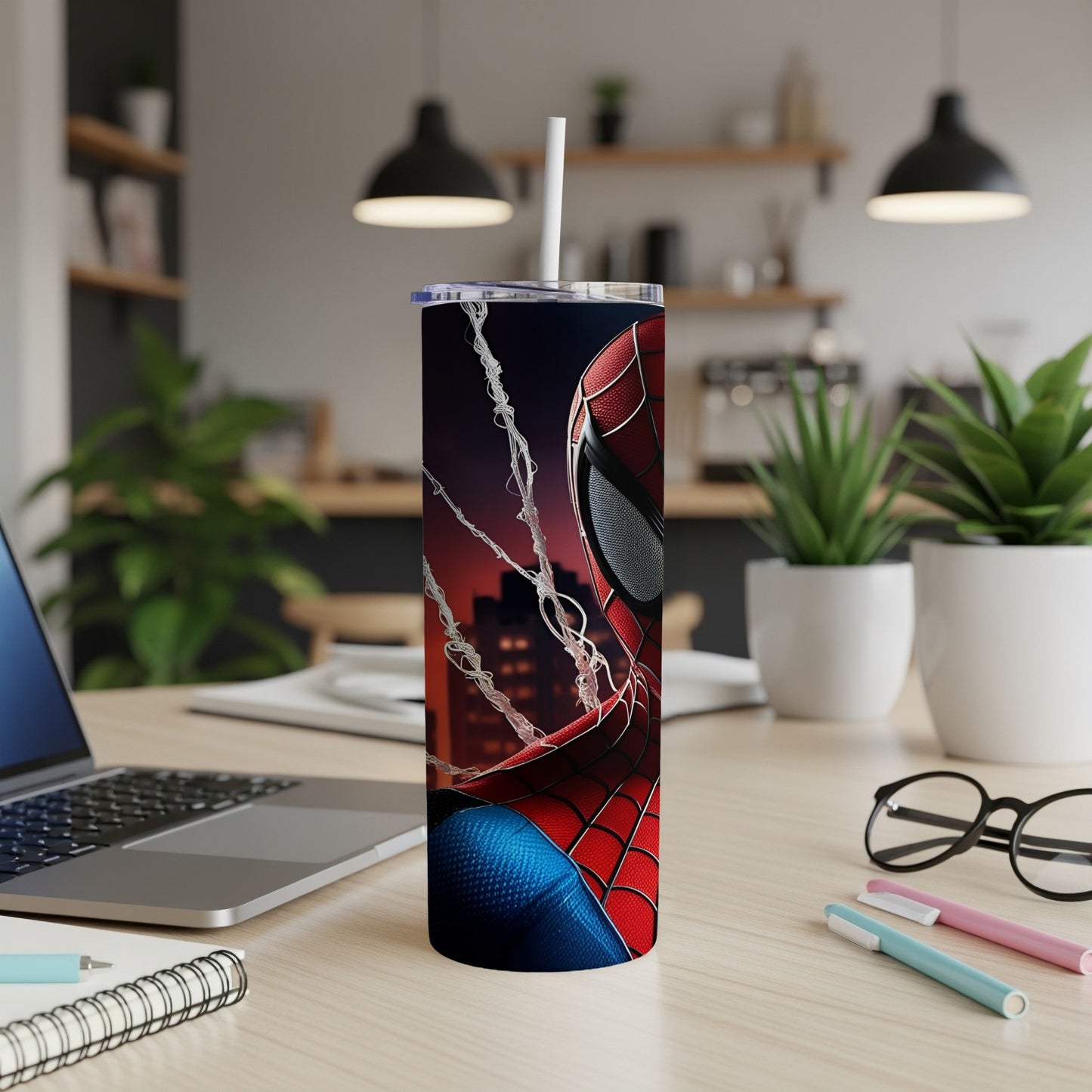 Spiderman tumbler with city skyline and webs on a desk.