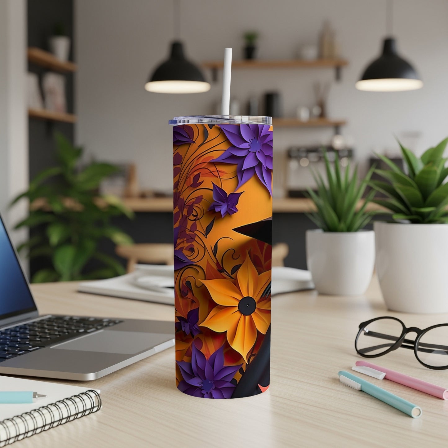 Tumbler with orange and purple floral design and white straw on a wooden desk.