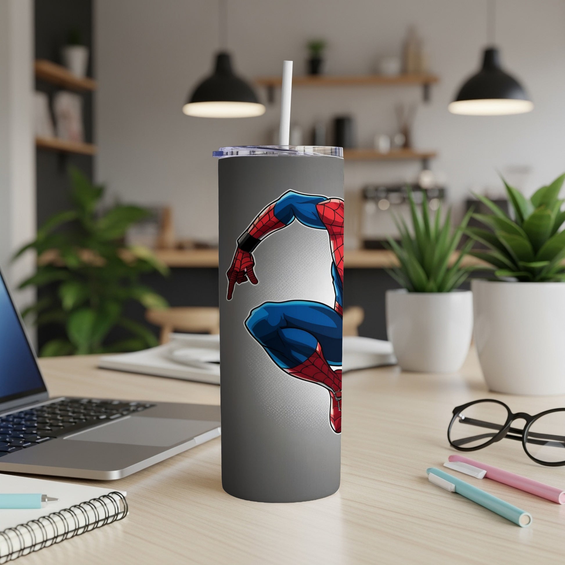 Spiderman on a gray tumbler with a white straw, on a desk.