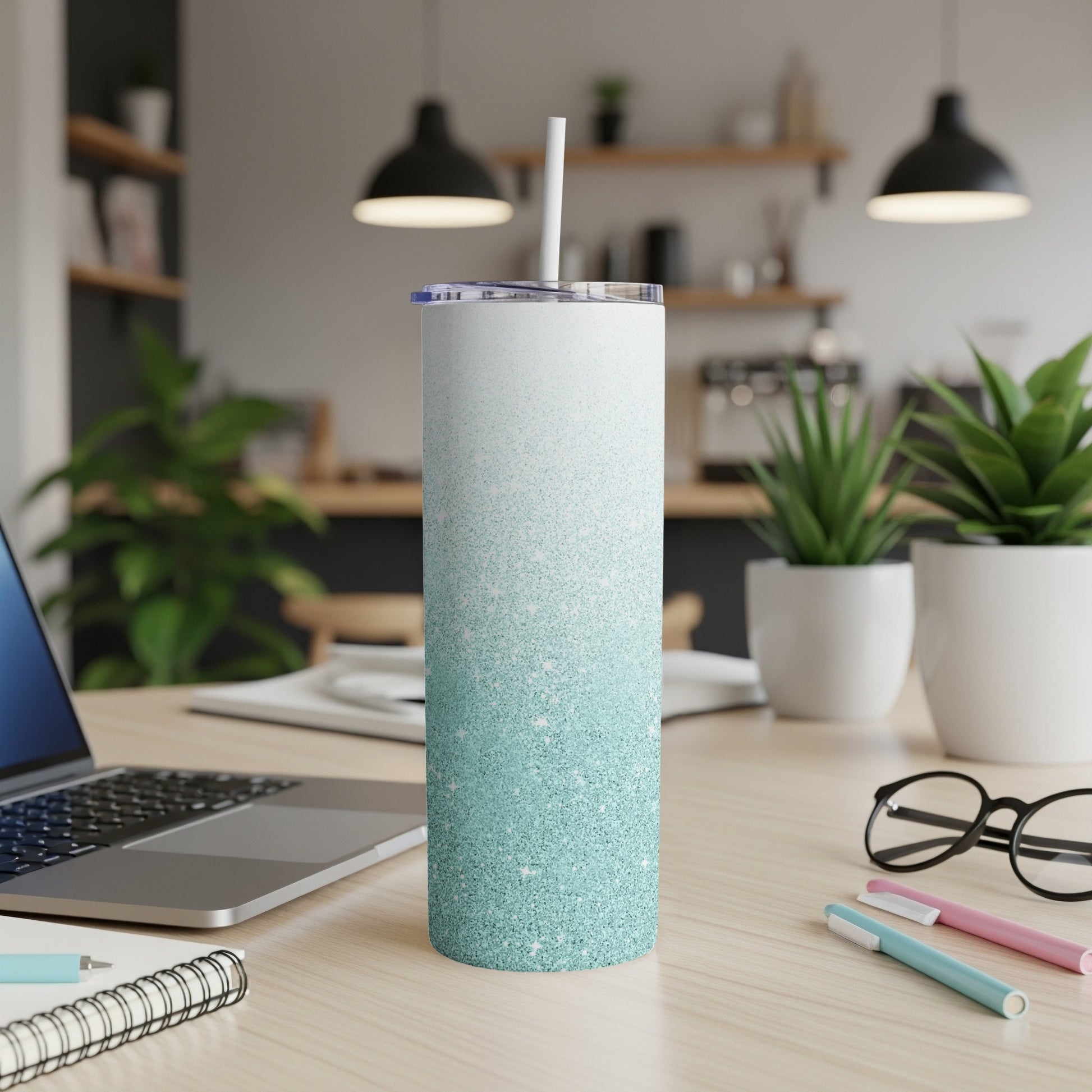 Glittery blue and white gradient skinny tumbler with straw on a desk.