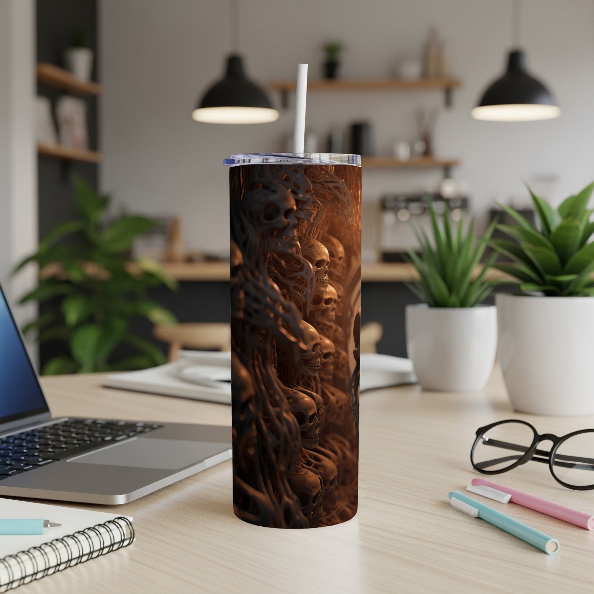 Tumbler with intricate skull and bone relief design on a wooden desk.