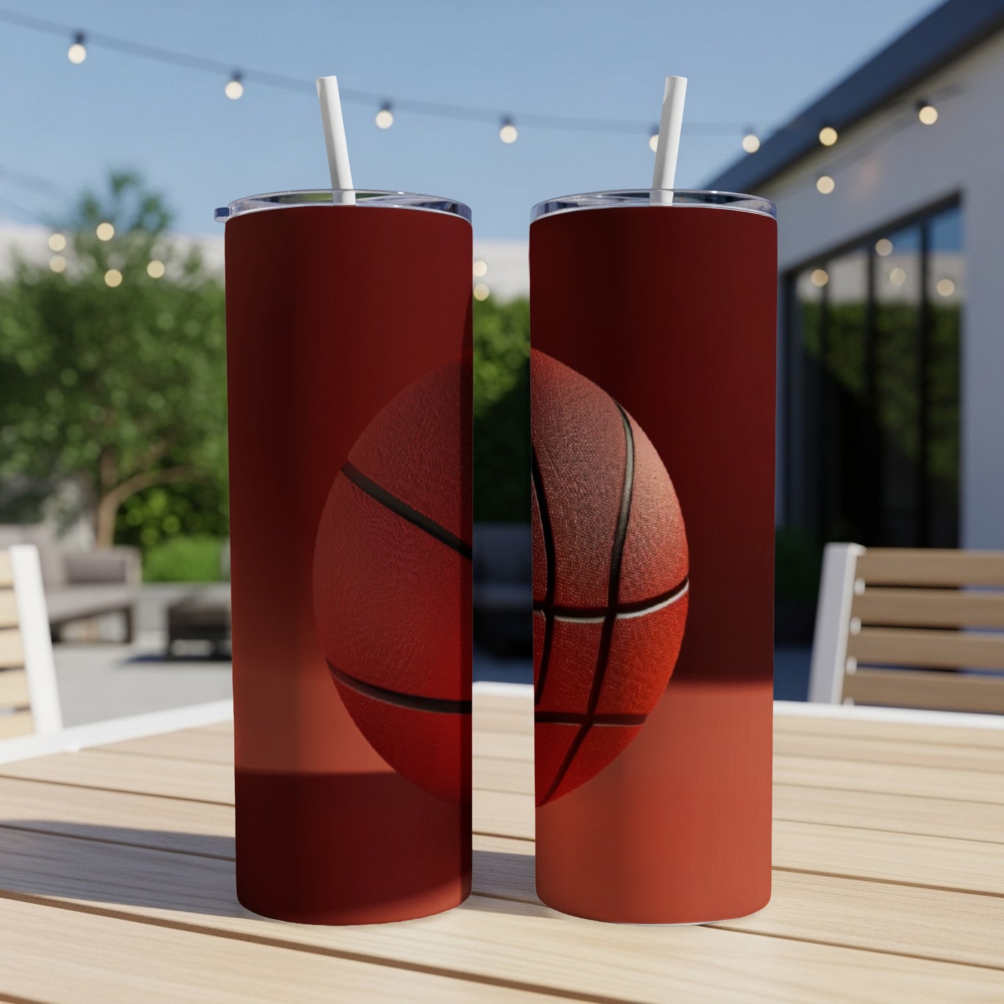 Two tall red tumblers with a basketball graphic on an outdoor table.
