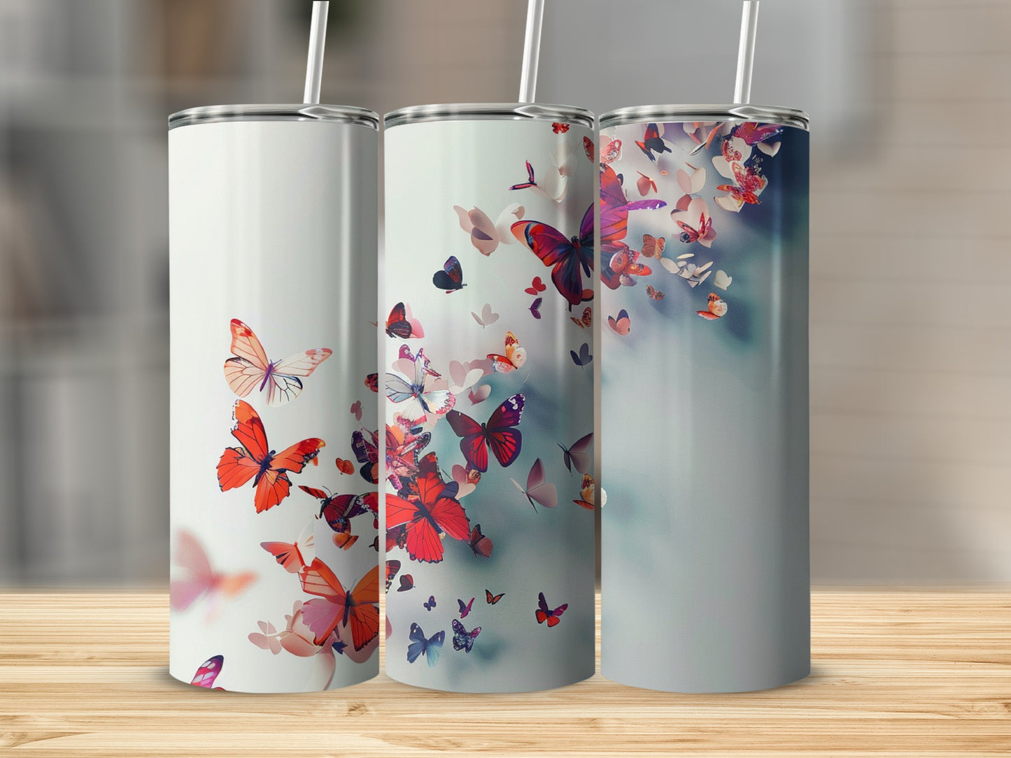Three tumblers with red and pink butterflies on a wooden surface.