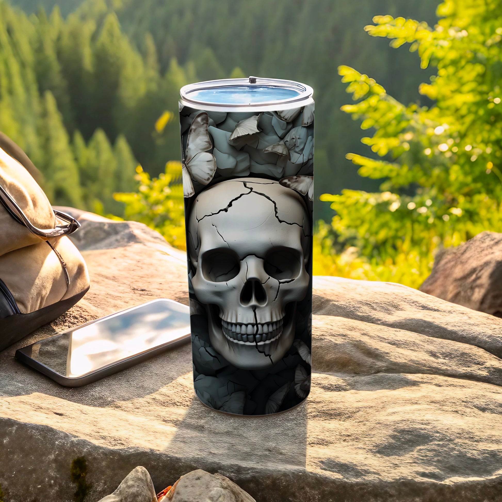 Skull and butterflies on a tumbler next to a backpack and phone.